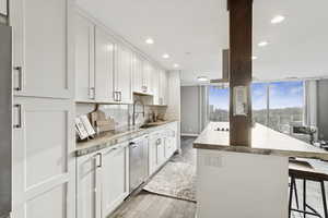 Kitchen featuring a kitchen breakfast bar, white cabinets, light wood-style flooring, recessed lighting, and decorative backsplash