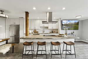 Kitchen with decorative backsplash, white cabinetry, high end fridge, recessed lighting, and island range hood