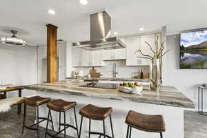 Kitchen with backsplash, white cabinets, island range hood, a kitchen breakfast bar, and recessed lighting