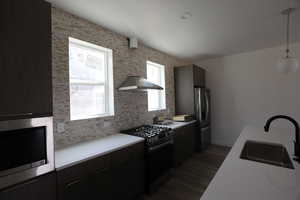 Kitchen featuring appliances with stainless steel finishes, light countertops, modern cabinets, hanging light fixtures, and dark wood-style flooring