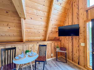 Living area featuring wooden walls, wood finished floors, vaulted ceiling, and wood ceiling