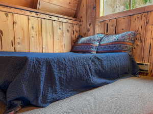 Carpeted bedroom with wood walls and vaulted ceiling
