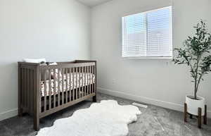 Carpeted bedroom featuring a crib and baseboards