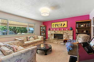 Living area featuring carpet flooring, a textured ceiling, and a fireplace