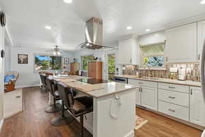 Kitchen with a kitchen breakfast bar, white cabinets, a center island, light stone countertops, and recessed lighting