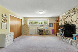 Carpeted office featuring a wood stove and a textured ceiling