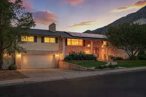 View of front of house featuring roof mounted solar panels, driveway, brick siding, and a garage