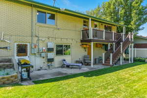 Back of property featuring a patio, stairway, brick siding, and a yard