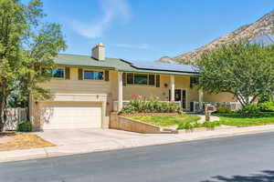 Bi-level home featuring covered porch, solar panels, brick siding, concrete driveway, and a garage