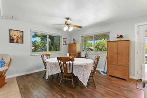 Dining area with ceiling fan, wood finished floors, and a textured ceiling