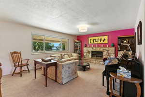 Carpeted living area with a fireplace and a textured ceiling