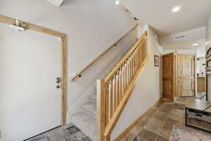 Stairs with recessed lighting and stone finish flooring
