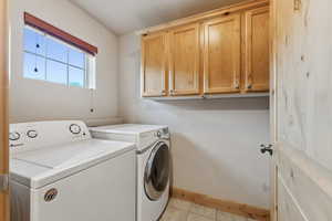 Laundry area with cabinet space, independent washer and dryer, and light tile patterned floors