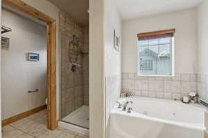 Full bath featuring a jetted tub, a stall shower, and tile patterned floors