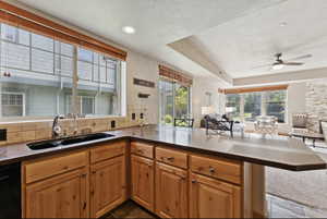 Kitchen with open floor plan, a tray ceiling, tasteful backsplash, a peninsula, and dishwasher
