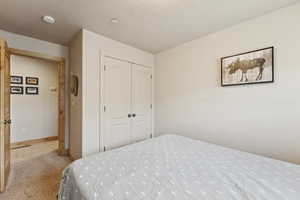 Carpeted bedroom featuring a closet and baseboards