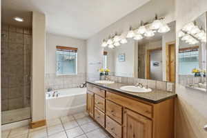 Full bathroom with tile patterned flooring, double vanity, a bath, a shower stall, and tile walls