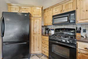 Kitchen with black appliances, tasteful backsplash, and light brown cabinetry