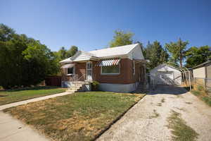 Bungalow with an outdoor structure, a garage, driveway, and brick siding