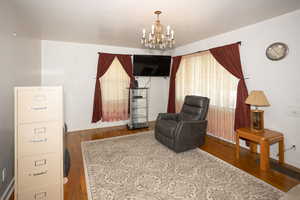 Sitting room with a chandelier and dark wood-type flooring