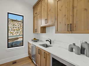 Kitchen with light stone counters, light wood finished floors, stainless steel fridge, and light brown cabinets