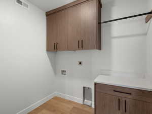 Laundry room featuring light wood-style flooring, cabinet space, electric dryer hookup, and washer hookup