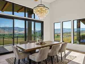 Dining space featuring a mountain view, light wood finished floors, a towering ceiling, and a chandelier