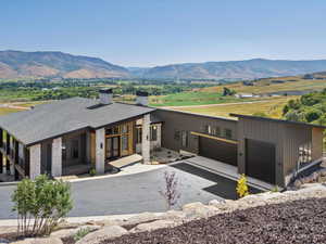 Modern home with a chimney, stone siding, an attached garage, and a mountain view