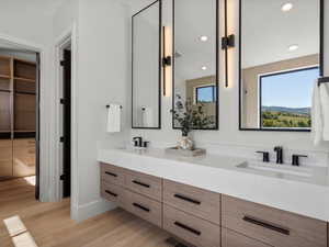 Bathroom with double vanity, recessed lighting, light wood-style floors, and a closet