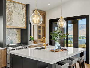 Kitchen featuring decorative backsplash, hanging light fixtures, glass insert cabinets, a breakfast bar area, and light stone countertops