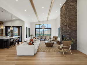 Living area with a chandelier, beam ceiling, a stone fireplace, light wood finished floors, and a mountain view