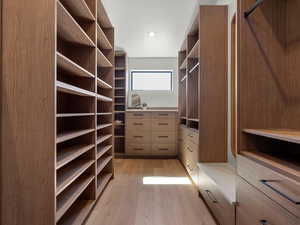 Walk in closet with light wood finished floors
