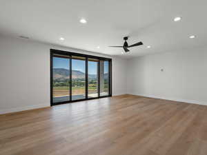 Unfurnished room with a mountain view, light wood-style flooring, recessed lighting, and ceiling fan