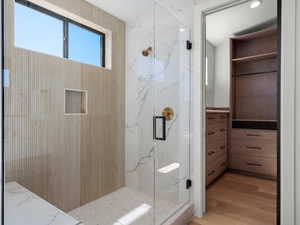 Full bath featuring a marble finish shower and light wood-style flooring