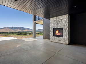 View of patio with a mountain view and an outdoor stone fireplace