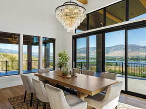 Dining room with wood finished floors, a water and mountain view, a chandelier, and a towering ceiling