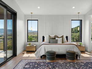 Bedroom with access to outside, recessed lighting, a decorative wall, and wood finished floors
