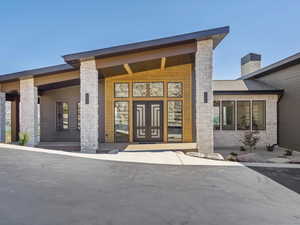 Doorway to property featuring a chimney and stone siding