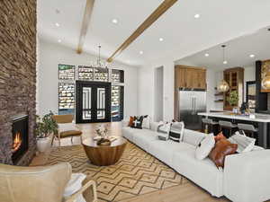 Living area featuring light wood-style floors, plenty of natural light, a stone fireplace, a chandelier, and recessed lighting