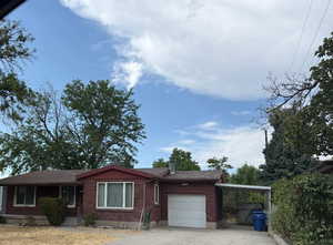 Ranch-style house featuring brick siding, driveway, a chimney, an attached garage, and a carport