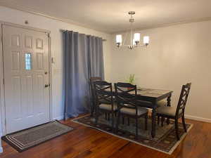 Dining room with dark wood finished floors, ornamental molding, and a chandelier