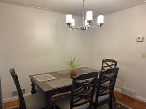 Dining room featuring dark wood-style floors, ornamental molding, and a chandelier