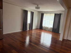 Spare room with plenty of natural light, dark wood-style flooring, a textured ceiling, and ornamental molding