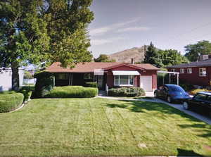 Ranch-style home featuring a garage, a front yard, concrete driveway, and a mountain view