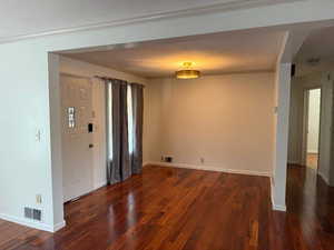 Entryway featuring crown molding, dark wood-type flooring, and a textured ceiling