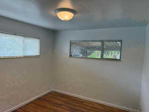 Empty room with baseboards and dark wood-type flooring