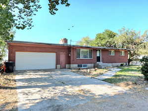 Ranch-style home with brick siding, a garage, a chimney, and concrete driveway