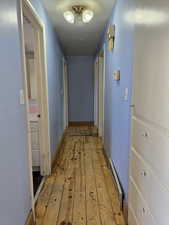 Hallway leading to 3 main level bedrooms, featuring light wood-type flooring