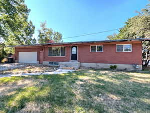 Ranch-style home with brick siding, a garage, a front yard, and concrete driveway