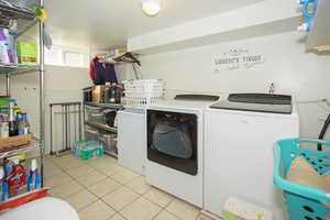 Washroom with light tile patterned flooring and washer and clothes dryer
